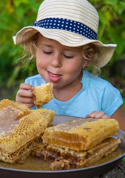 A child eats honey from a comb. Selective focus. Kid.
