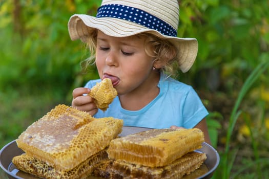 A child eats honey from a comb. Selective focus. Kid.