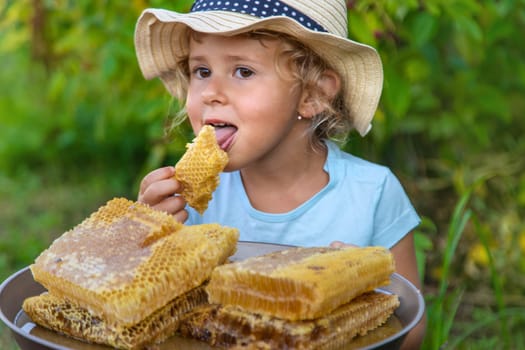 A child eats honey from a comb. Selective focus. Kid.