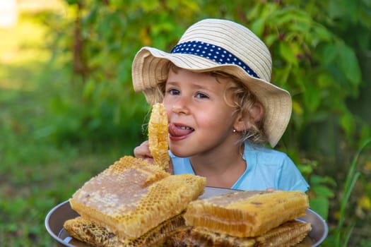 A child eats honey from a comb. Selective focus. Kid.