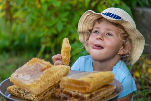 A child eats honey from a comb. Selective focus. Kid.