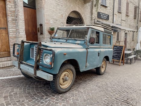 Cremona, Lombardy, Italy October 15th 2024 Light blue vintage land rover series iii parked on cobblestone street in front of a traditional italian restaurant