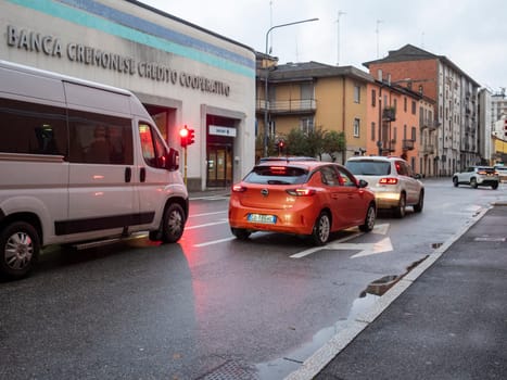 Cremona, Lombardy, Italy October 15th 2024 Cars stopping at a red traffic light on a city street, with a banca cremonese credito cooperativo building in the background
