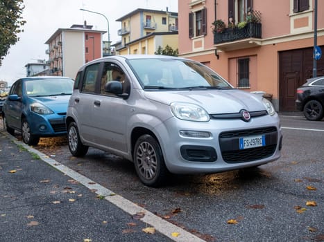 Cremona, Lombardy, Italy October 15th 2024 Silver fiat panda parked correctly on the side of a street in an urban environment next to a blue renault clio