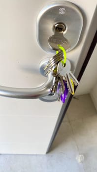 Cremona, Lombardy, Italy October 15th 2024 Bunch of keys hanging from keyhole on white door, concept of security, house, and ownership