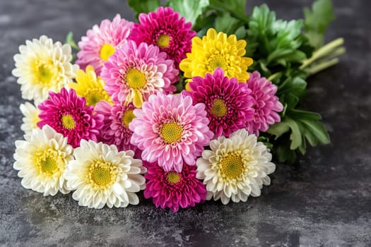 A vibrant collection of chrysanthemums in shades of pink, yellow, and white is beautifully arranged, resting on a dark surface that enhances their colors and freshness.