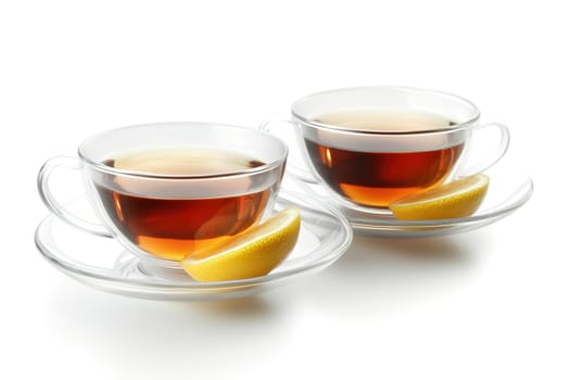 Two clear glass cups filled with dark tea are accompanied by lemon wedges, creating a refreshing beverage presentation on a white background.