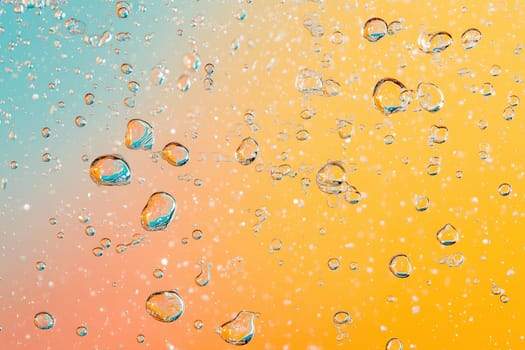 Droplets of water are suspended in the air, reflecting light as they rise against a colorful gradient background of blue and orange. The setting evokes a sense of freshness and vitality.