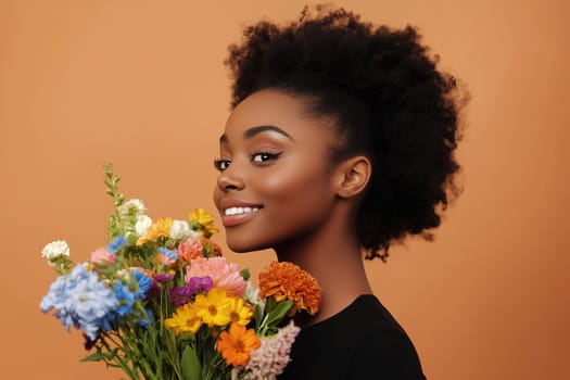 A woman with a joyful expression showcases a vibrant bouquet of flowers. Her natural afro hairstyle enhances the warm tones of the orange backdrop, creating a cheerful atmosphere.