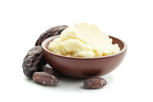A bowl filled with creamy natural shea butter is placed beside several raw cocoa seeds. The setup emphasizes the ingredients' organic origins for skincare and cosmetic purposes.