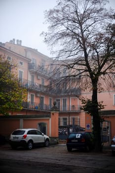 Cremona, Lombardy, Italy - November 7th 2024 Fog covering residential building with parked cars in courtyard on a fall morning