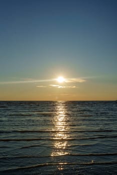 A peaceful sunset over a calm ocean with gentle waves and a colorful sky, creating a tranquil and scenic landscape. The image captures the beauty of twilight with no people in view.