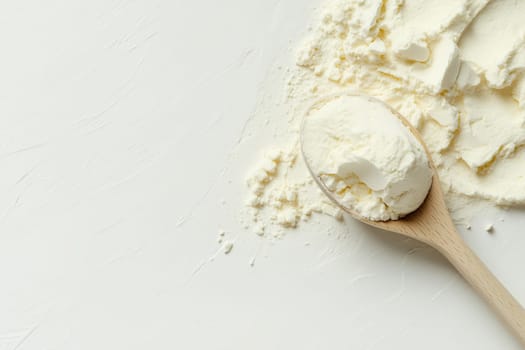 A wooden spoon holds a generous amount of flour, placed on a smooth white surface. The flour is finely textured and looks ideal for various baking and cooking tasks.