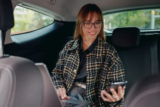 A professional woman engaged in work while traveling in a car, showcasing multitasking and productivity.