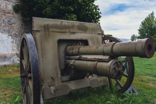 An antique military cannon with rusted metal parts, displayed outdoors on a green field, highlighting its historical significance and aged appearance as a relic of military history