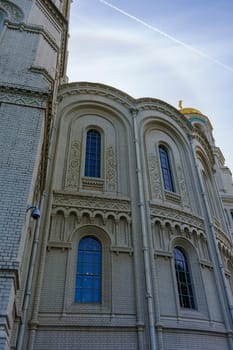 The exterior of a historic cathedral showcasing ornate architectural details, including arched windows and intricate stonework, set against a clear blue sky