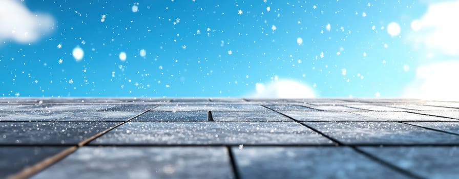 Snow gently falling on rooftop under bright blue sky.
