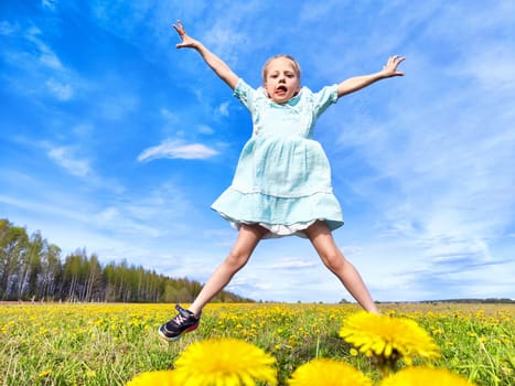 A girl in a light dress jumps excitedly among bright dandelions on a sunny day, enjoying the beauty of nature.