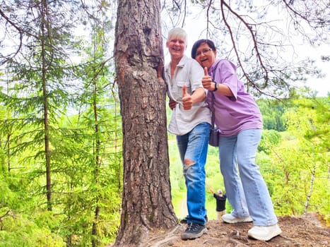 A couple clings to each other and a tree as they confront their fear of heights in the mountain landscape