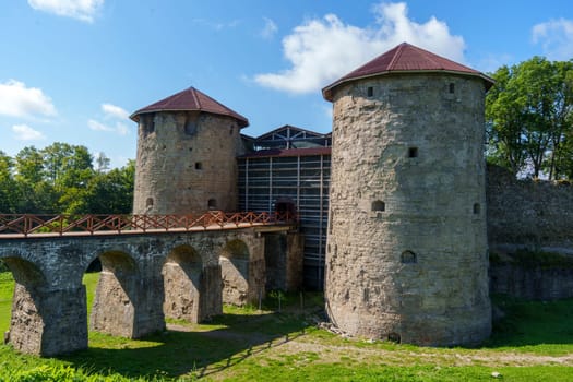Close-up view of ancient stone fortress towers connected by a bridge and featuring arched entrances, set against a clear blue sky. Historic architecture and medieval charm
