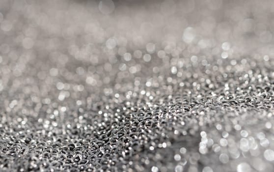 Silver glitter background material.Horizontal blurred metallic surface. Pure silver wire mesh. Wavy fabric with glitter. Used for backgrounds of fashion products