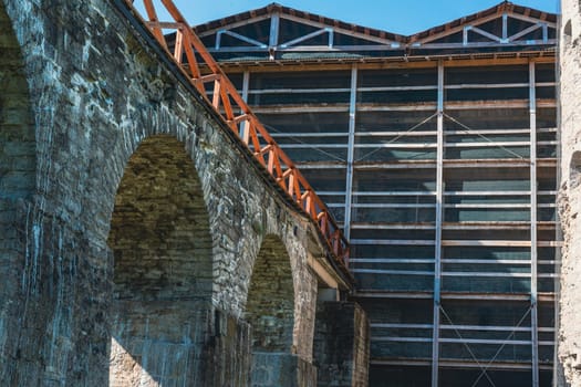 Close-up of a historic fortress with stone archways and a wooden structure, showcasing medieval architectural design and craftsmanship under a clear sky