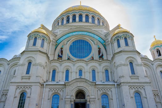 A grand cathedral with prominent golden domes and an ornate facade, displaying intricate architectural details under a bright blue sky, symbolizing cultural and spiritual heritage