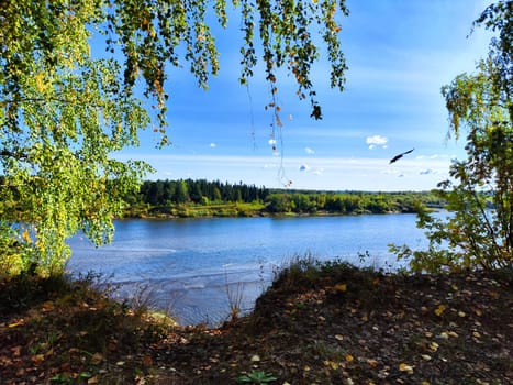 The picturesque river flows gently, surrounded by lush greenery and bathed in sunlight, evoking a peaceful spring atmosphere.