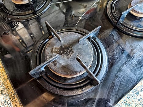 Worn burners on a black gas stove top in a home kitchen setting.