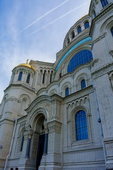 A detailed view of a historic cathedral's exterior, featuring a golden dome, arched windows, and an ornate entryway under a clear blue sky, showcasing architectural and cultural grandeur