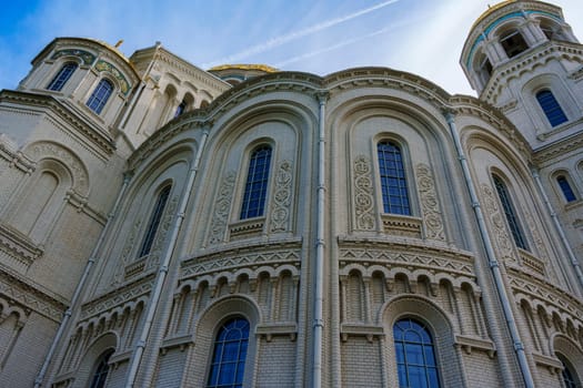 The exterior of a historic cathedral showcasing ornate architectural details, including arched windows and intricate stonework, set against a clear blue sky