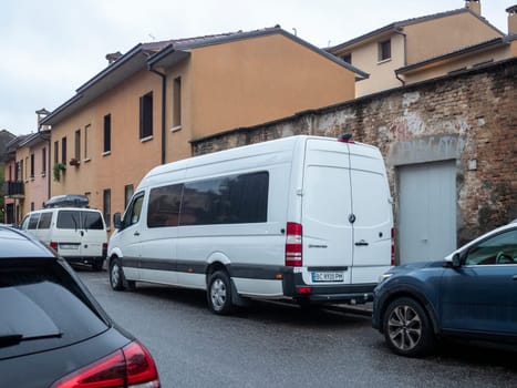Cremona, Lombardy, Italy October 15th 2024 White mercedes benz sprinter van parked on a narrow street in a residential area of an italian town, showcasing urban parking challenges