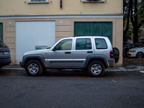 Cremona, Lombardy, Italy October 15th 2024 Silver jeep liberty parked on a quiet residential street in autumn, showcasing urban parking and automotive lifestyle