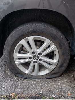 Cremona, Lombardy, Italy October 15th 2024 Deflated tire on a parked car symbolizes roadside trouble, emphasizing need for repair and the importance of road safety