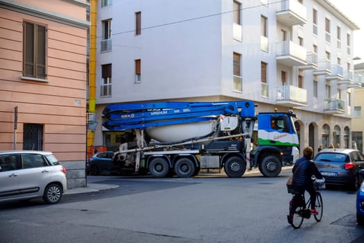 Cremona, Lombardy, Italy - November 7th 2024 Concrete mixer truck driving on a street in a residential area, passing a cyclist