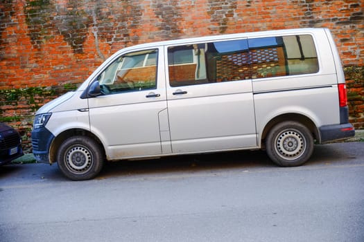 Cremona, Lombardy, Italy - November 7th 2024 Passenger van parked near an old brick wall, ideal for transporting people or goods