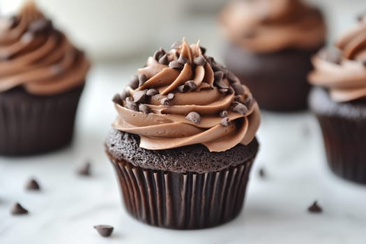 Chocolate cupcakes topped with rich chocolate frosting and sprinkled with mini chocolate chips are displayed invitingly. They are perfect for any celebration or sweet craving.