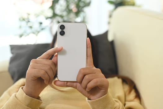 Close up of woman in yellow sweater typing message on her smartphone.