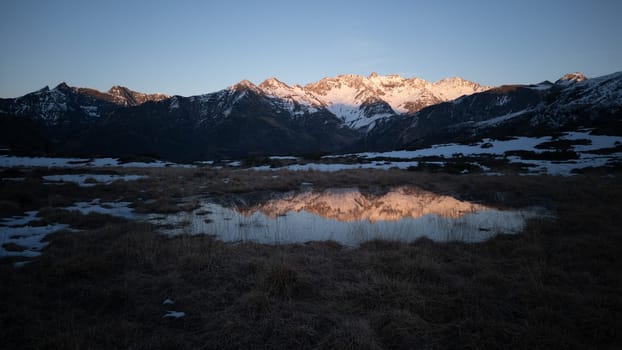 Sunset over the Pyrenees mountains with the reflection of the peaks in the water of the lake High quality 4k footage