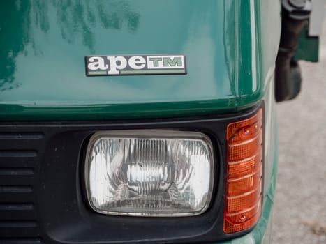 Arquato, PC, italy - October 31st 2024 Close up view of the front headlight and orange turn signal of a green ape piaggio scooter tm truck, highlighting the vehicle's branding and design