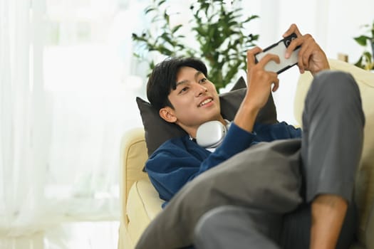 Young man with headphones playing video game on smartphone.