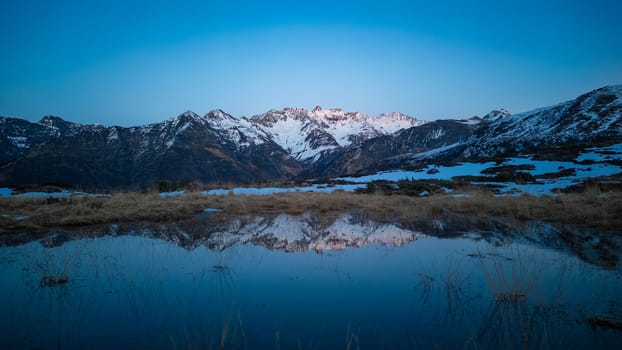 Sunset over the Pyrenees mountains with the reflection of the peaks in the water of the lake High quality 4k footage