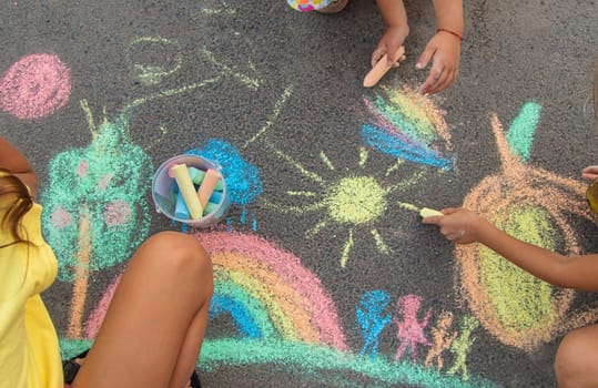 Children draw with chalk on the asphalt. Selective focus. kid.