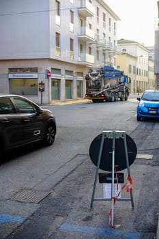 Cremona, Lombardy, Italy - November 7th 2024 Concrete mixer truck driving on a city street with a road closed sign in the foreground