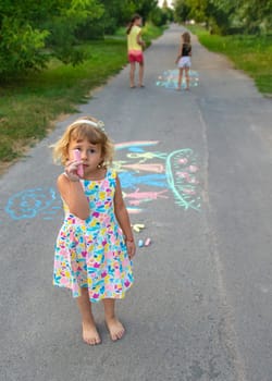Children draw with chalk on the asphalt. Selective focus. kid.