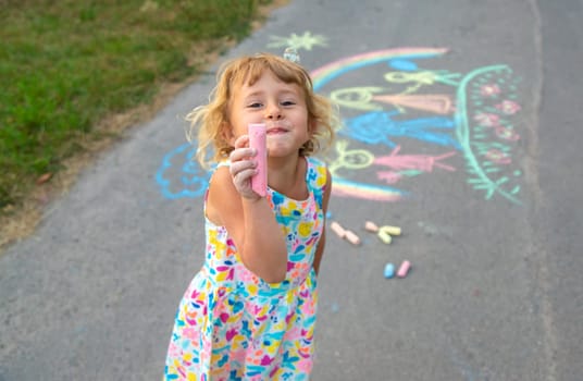 Children draw with chalk on the asphalt. Selective focus. kid.