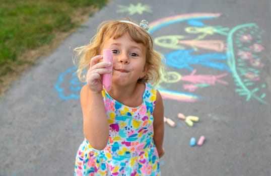 Children draw with chalk on the asphalt. Selective focus. kid.