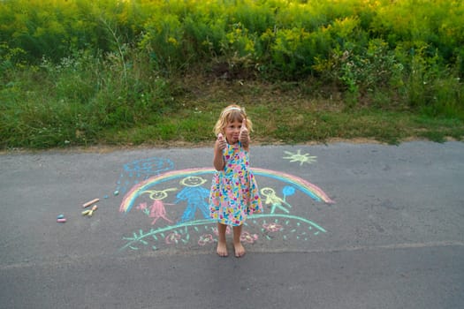 Children draw with chalk on the asphalt. Selective focus. kid.
