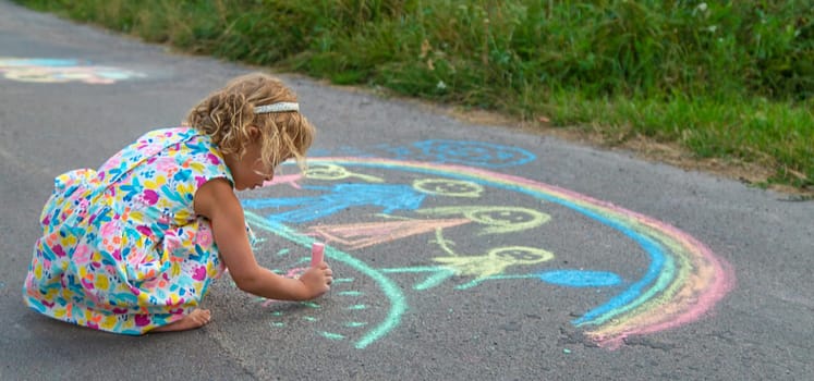 Children draw with chalk on the asphalt. Selective focus. kid.