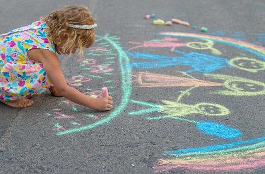 Children draw with chalk on the asphalt. Selective focus. kid.